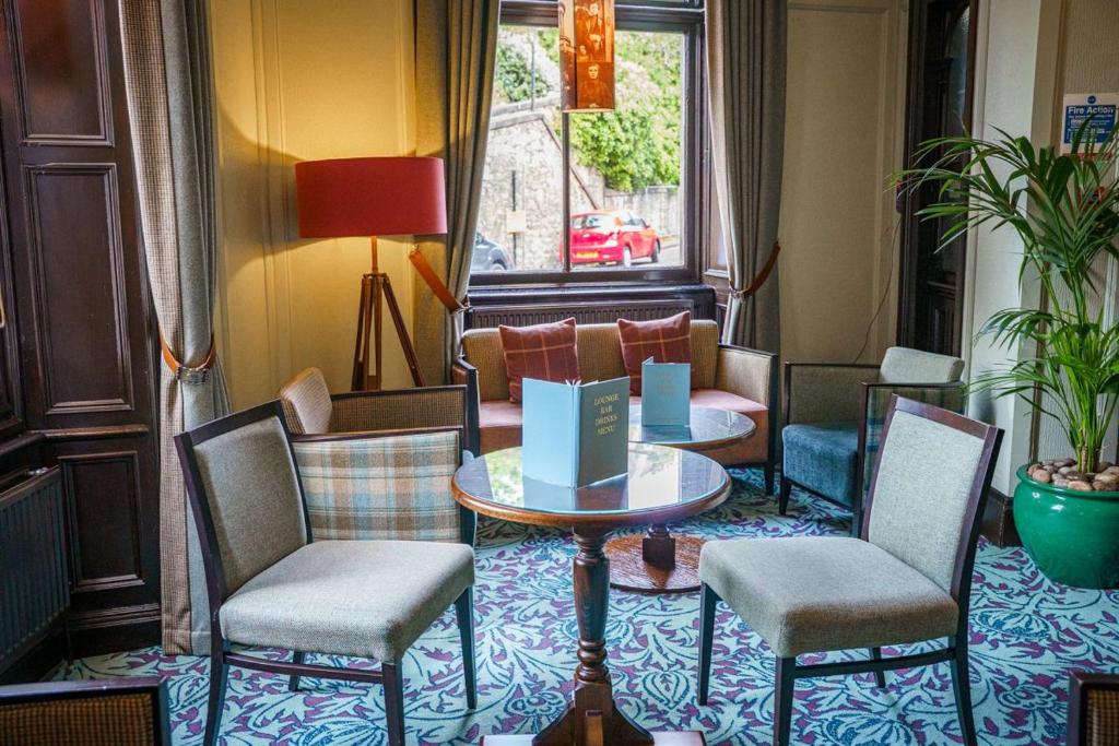Poltronas com estampa xadrez ao redor de mesas redondas em um ambiente aconchegante no The Parliament House Hotel.