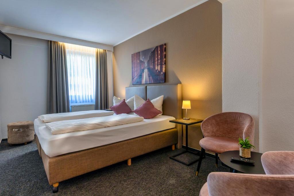 Quarto do Auto-Parkhotel Hamburg St. Pauli com cama de casal, poltronas rosadas de veludo e janela iluminada.