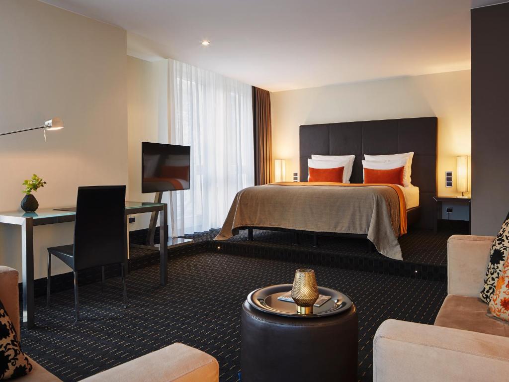 Suíte espaçosa em nível elevado com cama de casal ao fundo e área de estar com poltronas em Hamburgo.