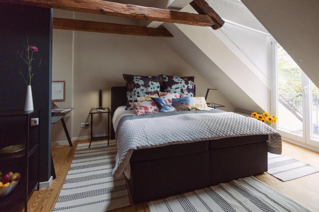 Quarto de sótão aconchegante com vigas de madeira expostas no teto e cama confortável com almofadas florais em Hamburgo.