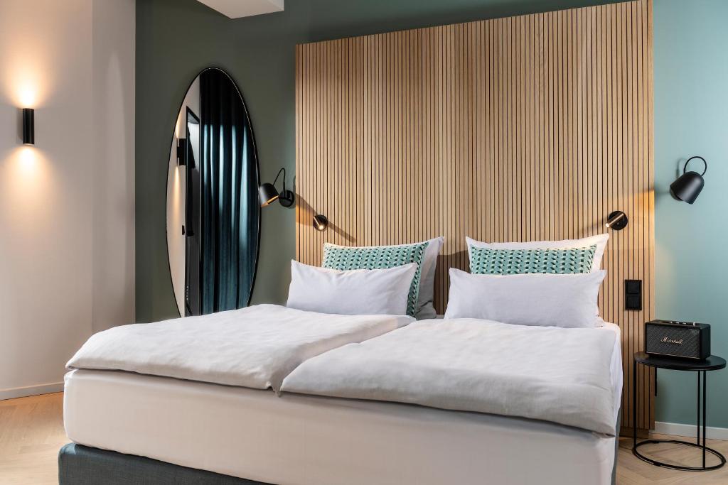 Quarto do Clipper Boardinghouse Hamburg-Michel com cabeceira de madeira ripada, espelho oval e tons suaves de verde.