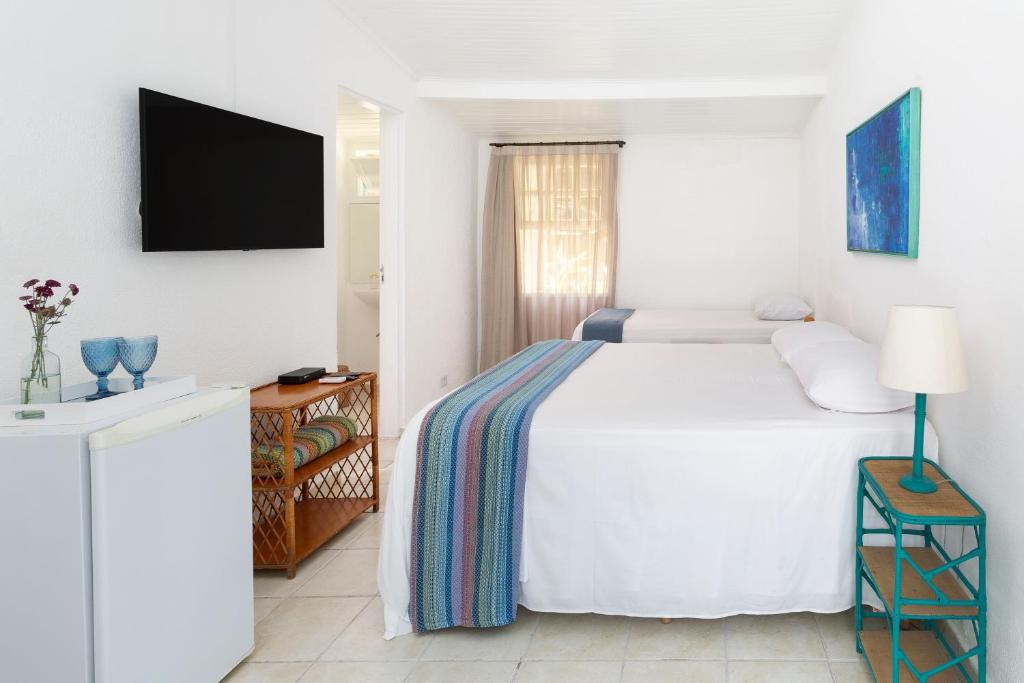 Quarto do Vila Siriúba Hotel, em Ilhabela, com duas camas e decoração clara em tons de azul.