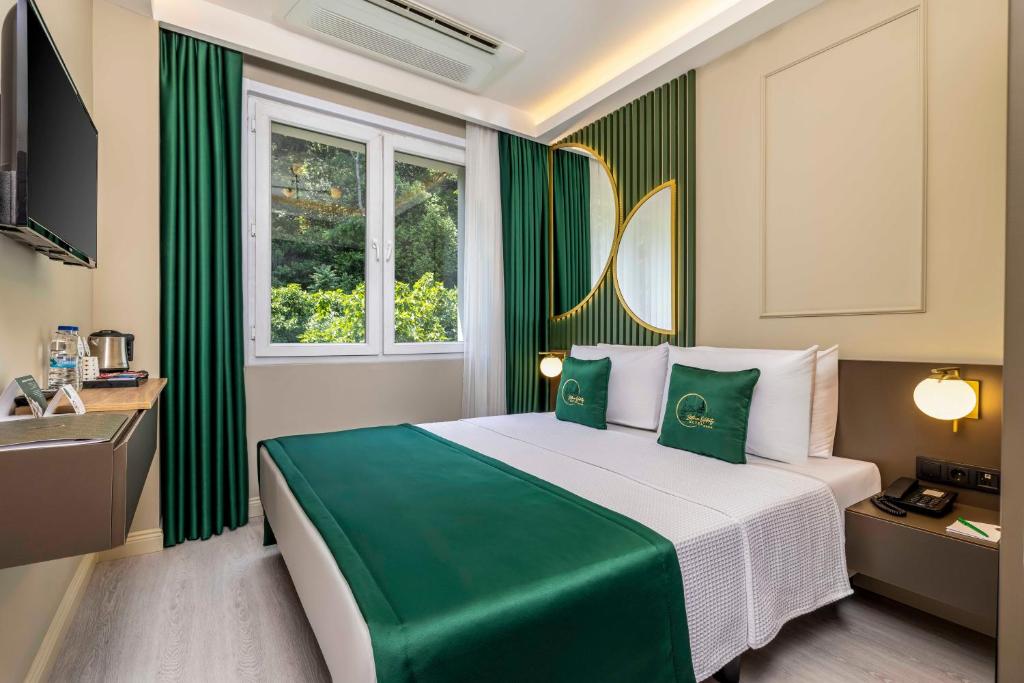 Quarto de casal do Sistina Old City Hotel, em Istambul, com detalhes verdes e janela voltada para árvores.