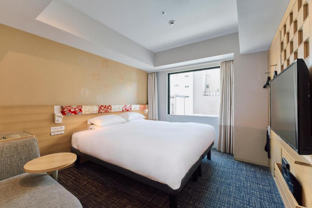 Quarto do Hotel Grand Bach Kyoto Select, em Kyoto, com duas camas unidas, poltrona e televisão.