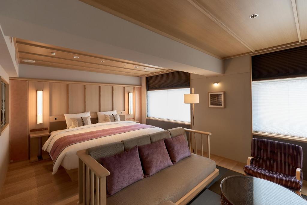 Quarto do Kyoto Century Hotel, em Kyoto, com cama de casal, sofá e decoração em tons claros e rosados.