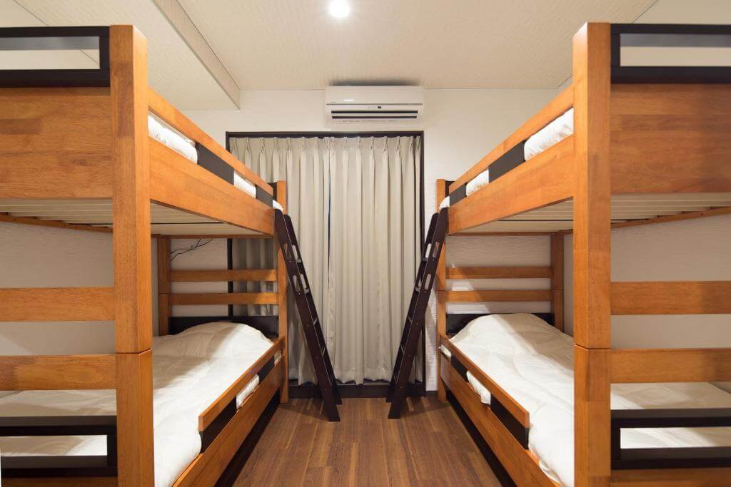 Quarto compartilhado do Ryokan Hostel Gion, em Kyoto, com dois beliches de madeira e quatro camas.