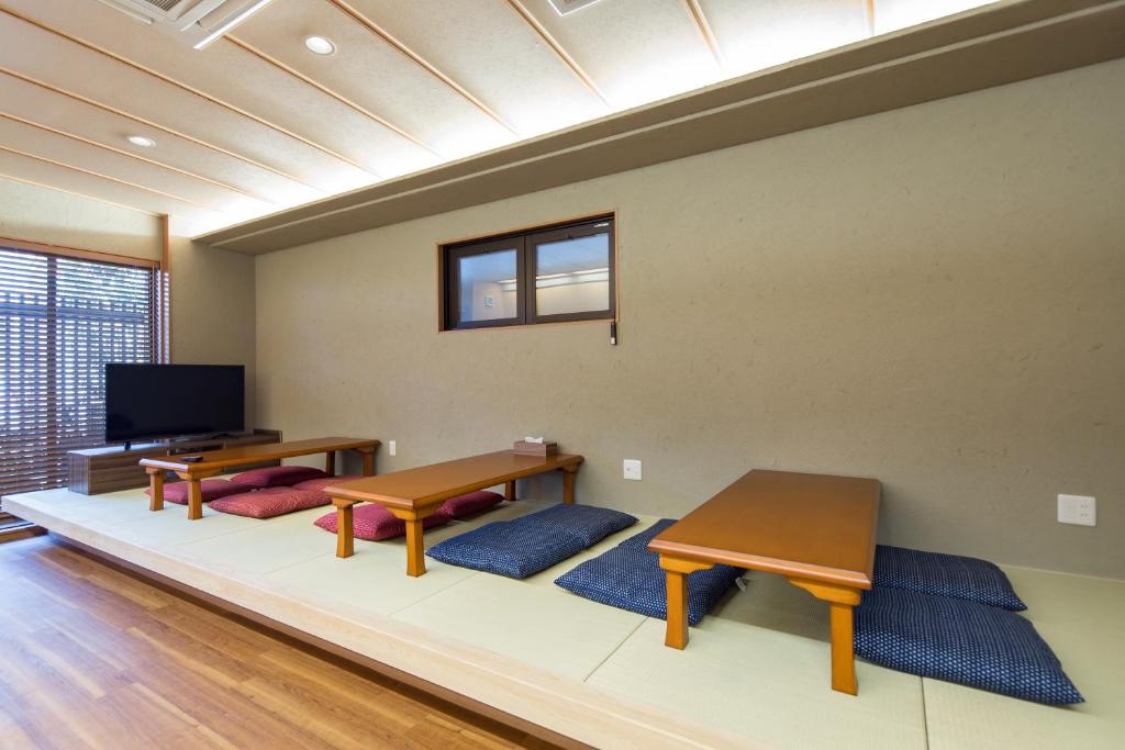 Área comum do Ryokan Hostel Gion, em Kyoto, com tatame, mesas baixas, almofadas e televisão.