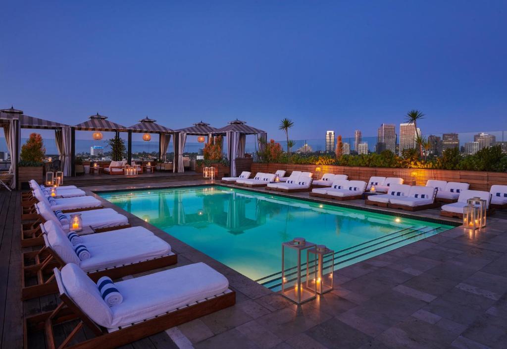 Piscina no rooftop do SIXTY Beverly Hills com espreguiçadeiras, cabanas e vista para prédios de Los Angeles