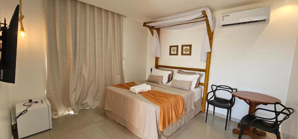 Quarto da Pousada Alkamar, em Maragogi, com cama de casal com dossel, mesa e ar-condicionado.