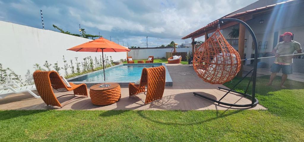 Área de lazer da Pousada Alkamar, em Maragogi, com piscina, cadeiras de fibra e balanço suspenso.