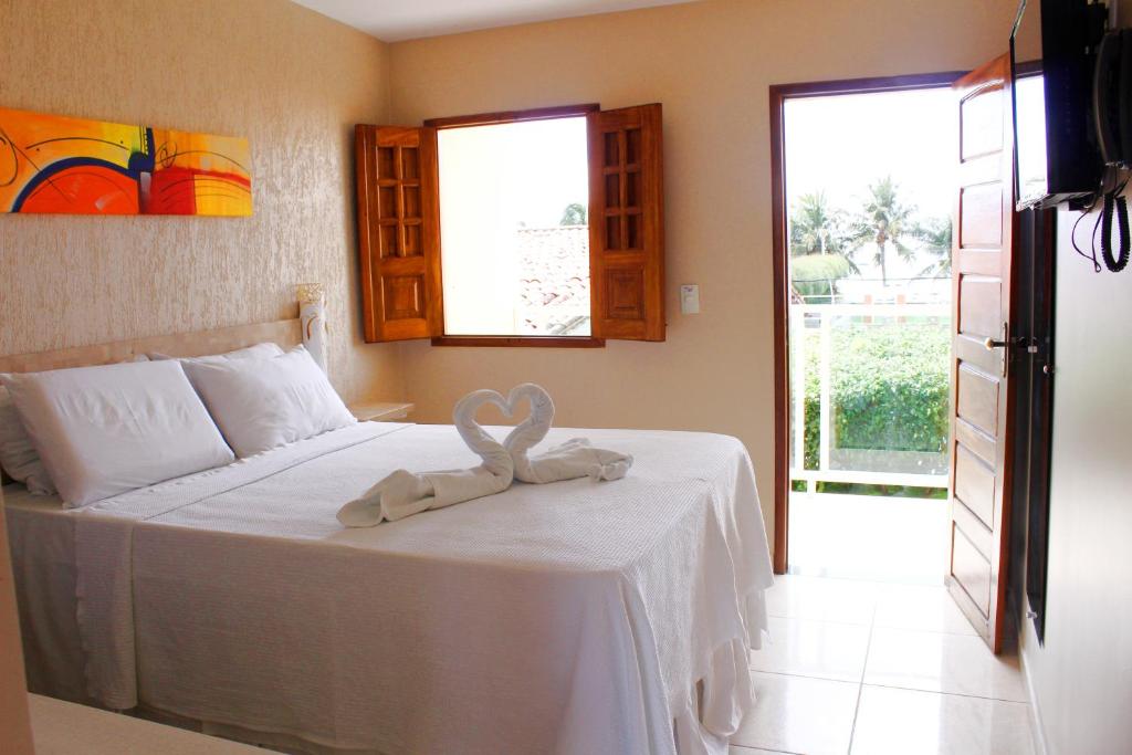 Quarto da Pousada Badejo, em Maragogi, com cama de casal, varanda e decoração em tons claros.