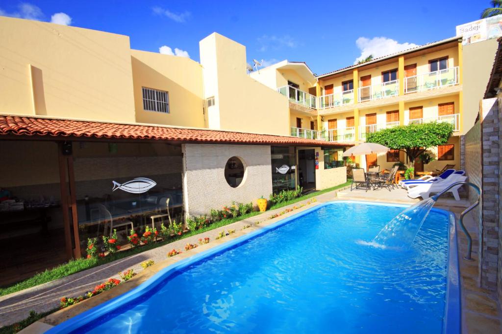 Área externa da Pousada Badejo, em Maragogi, com piscina, espreguiçadeiras e edifício da hospedagem ao fundo.
