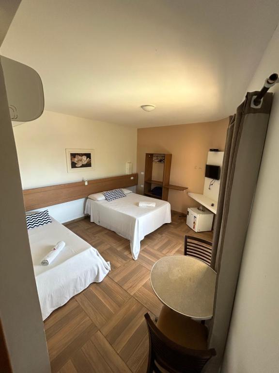 Quarto da Pousada Cellina's Mar, em Maragogi, com duas camas, mesa e frigobar.