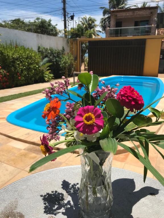 Piscina da Pousada Cellina's Mar, em Maragogi, com flores coloridas e jardim ao redor.