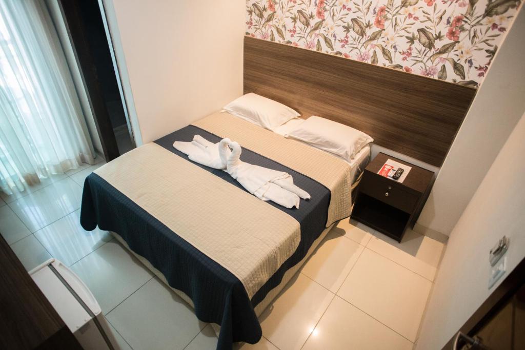 Quarto da Pousada Orla dos Corais, em Maragogi, com cama de casal e painel floral na cabeceira.