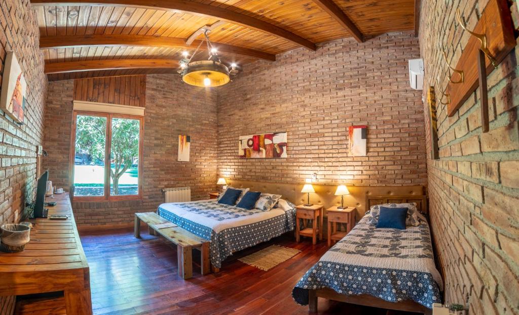 Quarto rústico no Luján de Cuyo B&B em Mendoza, com paredes de tijolos à vista, teto de madeira, cama de casal e cama de solteiro.