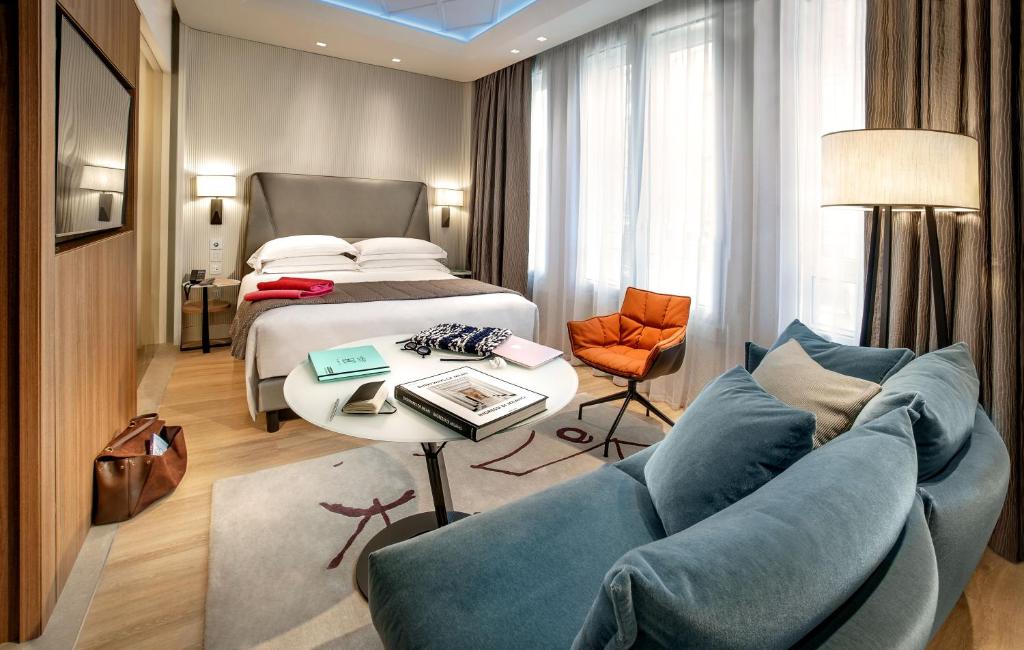 Quarto do Hotel Cavour, em Milão, com cama de casal, sofá azul e poltrona laranja