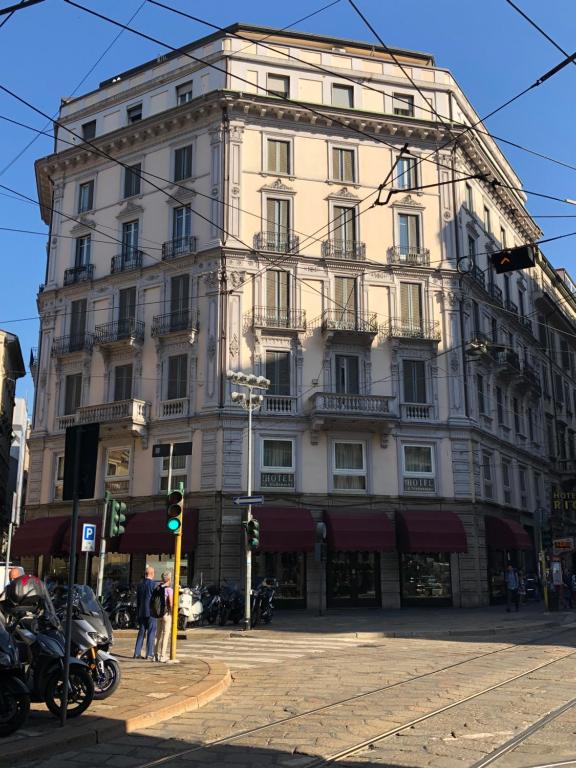 Fachada do Hotel La Madonnina, em Milão, em prédio de esquina com varandas e trilhos de bonde