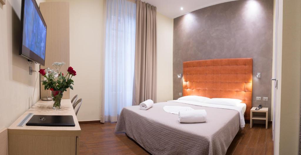 Quarto do Hotel La Madonnina, em Milão, com cama de casal, cabeceira laranja e mesa com TV