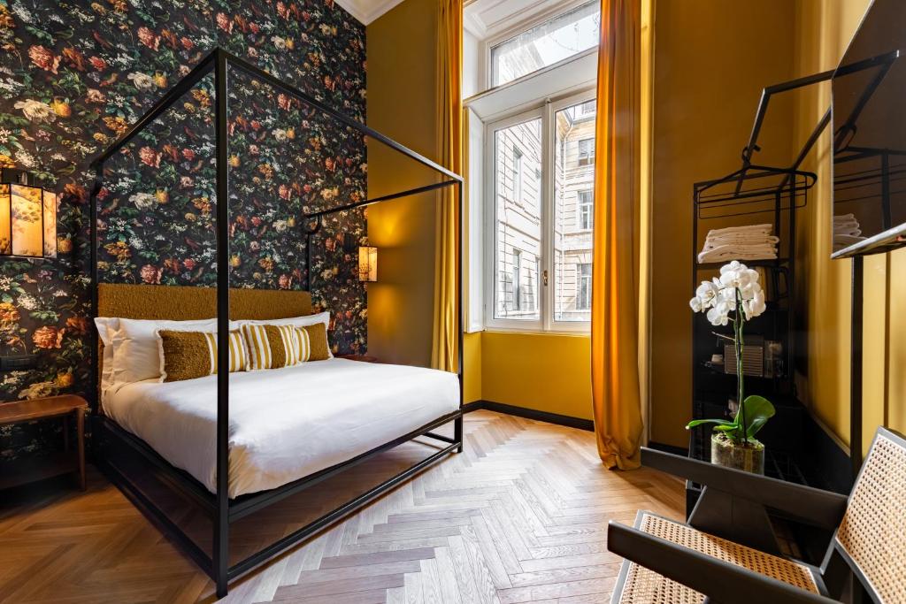 Quarto do Imperiale Suites Castello, em Milão, com cama de dossel, parede floral e cortinas amarelas