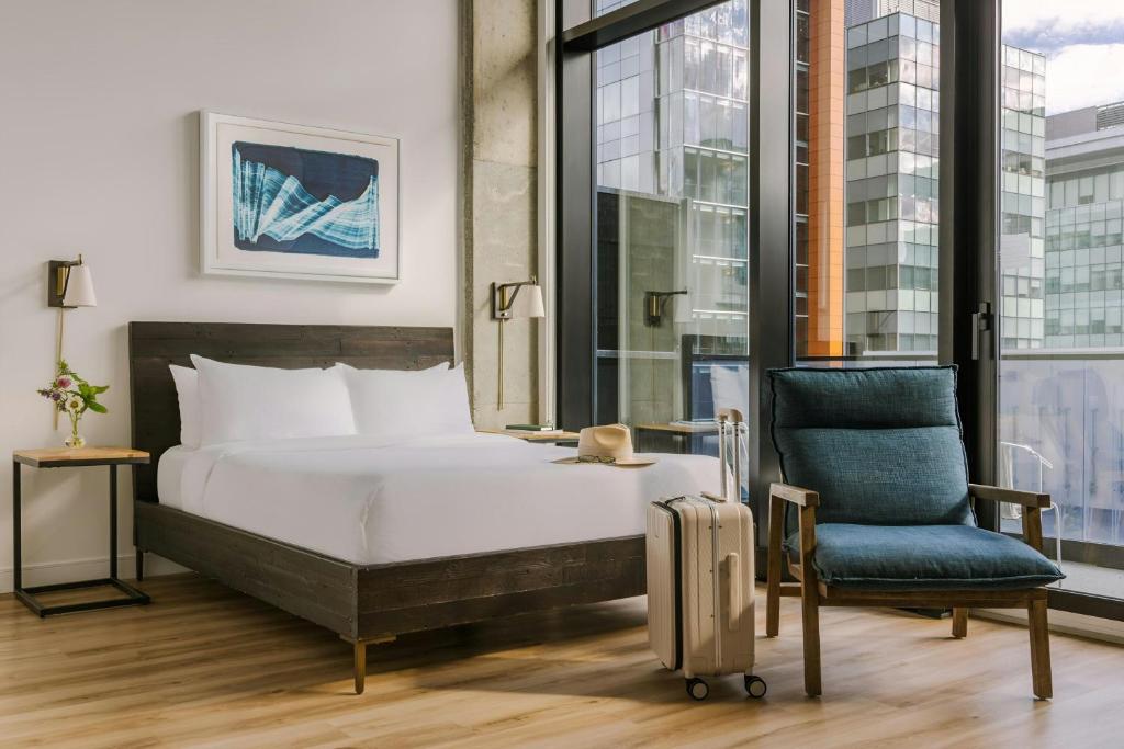 Quarto do Hotel Monville Downtown Montreal, em Montreal, com cama de casal e janelas do chão ao teto.