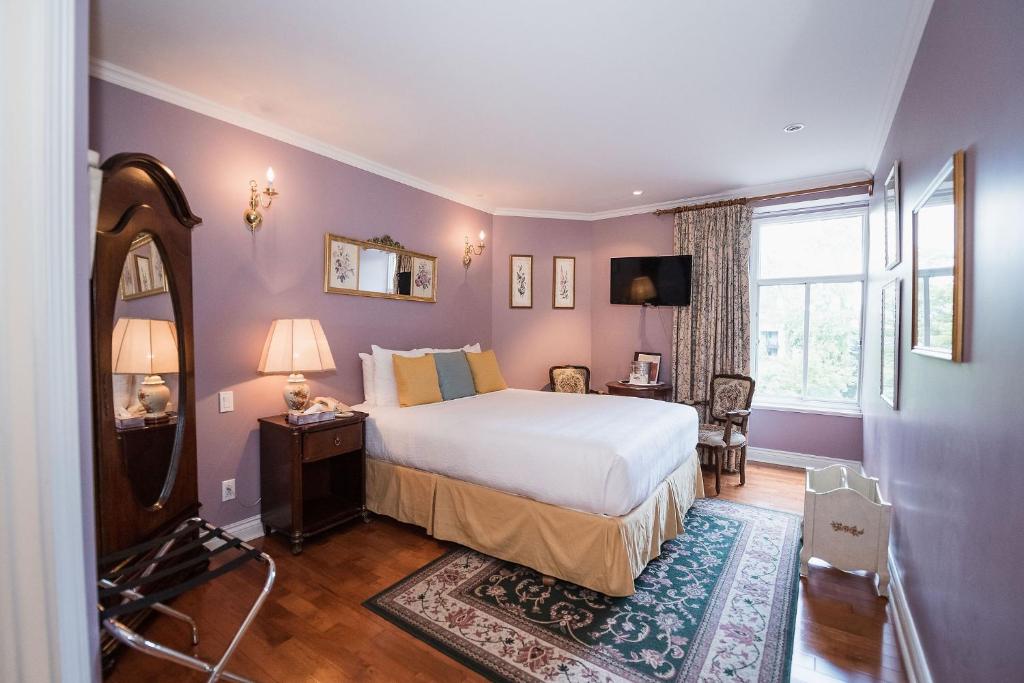 Acomodação do Manoir Sherbrooke, em Montreal, com cama de casal, móveis de madeira e paredes lilás.