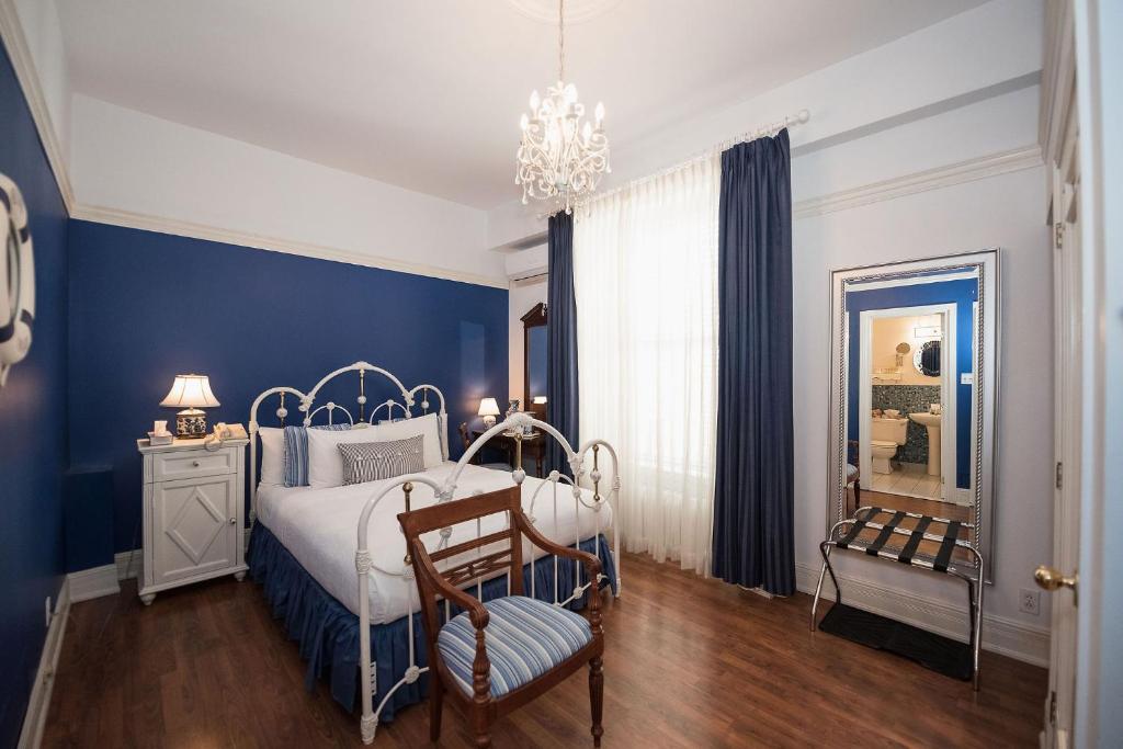 Quarto do Manoir Sherbrooke, em Montreal, decorado em azul e branco com cama de estrutura metálica.