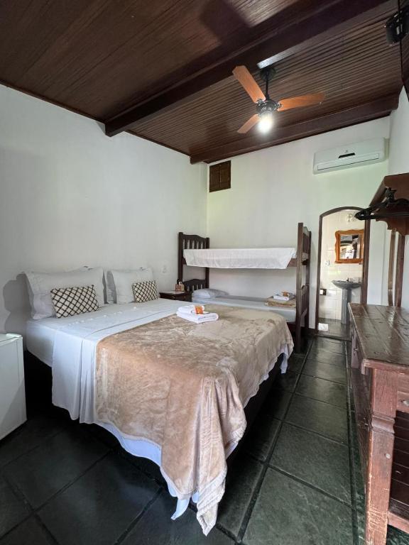 Quarto da Pousada Marendaz, em Paraty, com cama de casal, beliche de madeira e móveis rústicos.