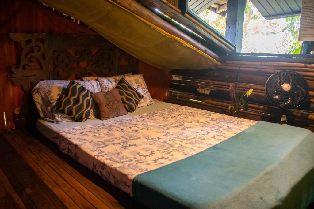 Quarto de madeira do ReMo Treehouse Hostel, em Paraty, com cama de casal e decoração rústica.