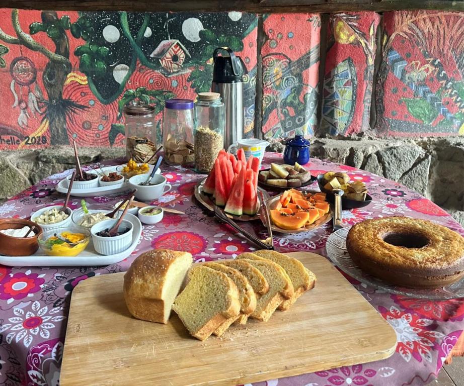 Café da manhã do ReMo Treehouse Hostel, em Paraty, com pães, frutas, bolo e acompanhamentos.