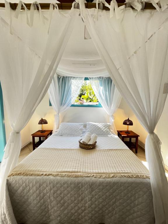 Quarto da Villa Tiê Paraty, em Paraty, com cama de casal envolvida por cortinas brancas.