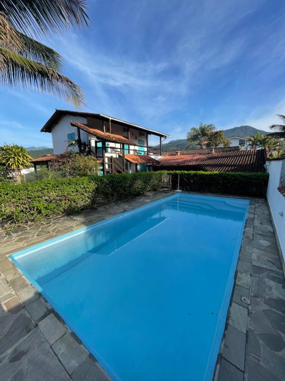 Piscina da Villa Tiê Paraty, em Paraty, cercada por vegetação e construções com telhados de cerâmica.