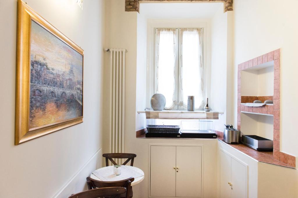 Área de refeições do Domus Trevi, em Roma, com mesa pequena, janela e bancada de apoio.