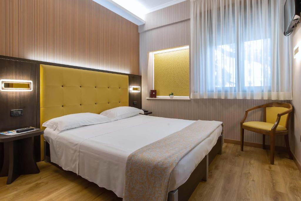 Quarto do Hotel Santa Prisca, em Roma, com cama de casal e cabeceira amarela.