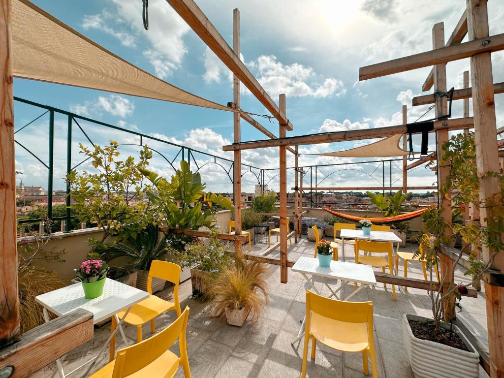 Terraço do Ostello Bello Roma Colosseo, em Roma, com mesas amarelas, plantas e rede.