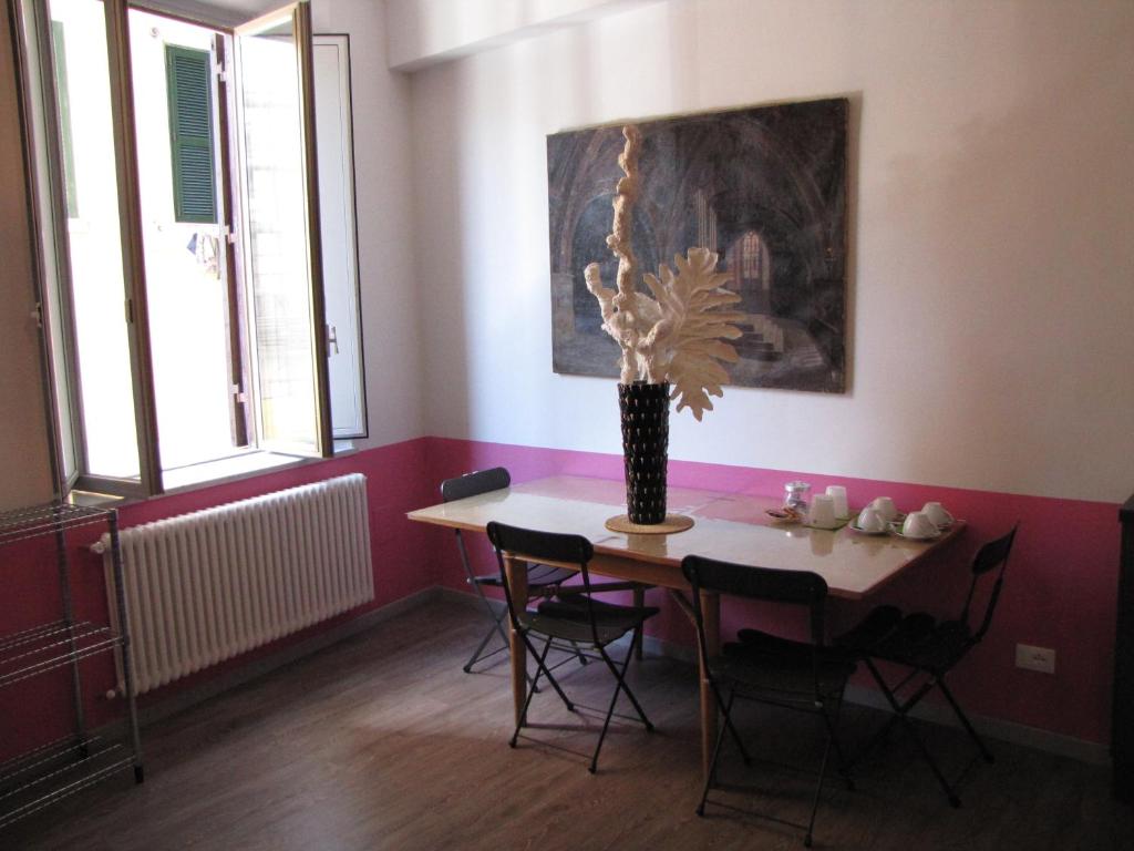 Sala de refeições do Trastevere Colors, em Roma, com mesa, cadeiras pretas e parede rosa.