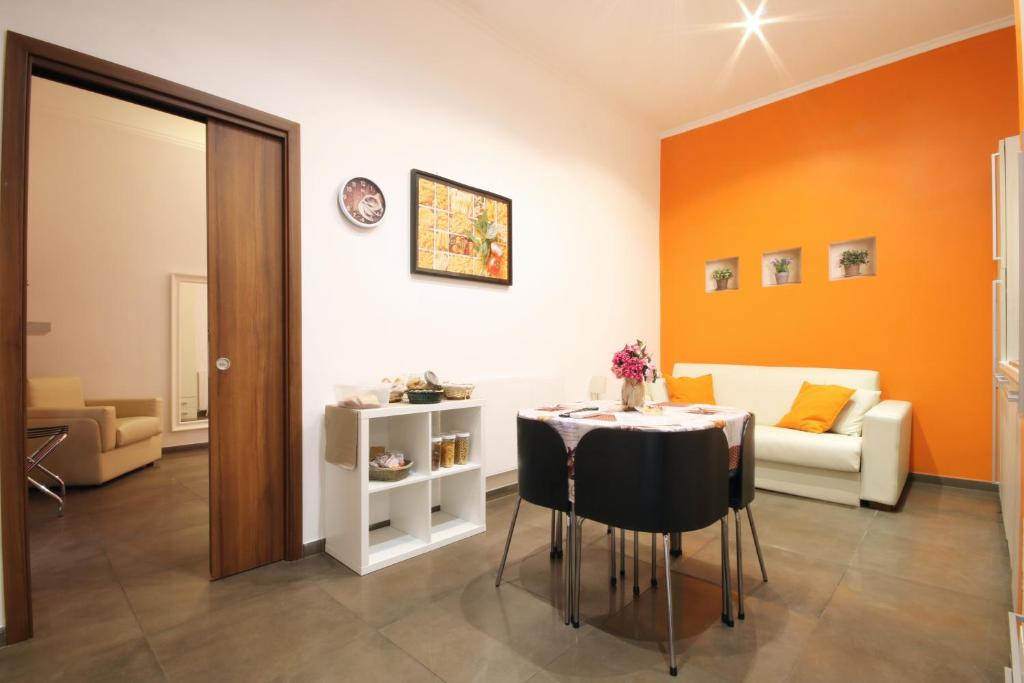 Sala de refeições do Vatication B&B, em Roma, com parede laranja, mesa e sofá branco.