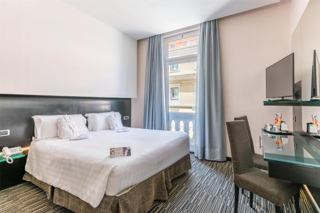 Quarto do Best Western Plus Hotel Universo, em Roma, com cama de casal, escrivaninha e janela alta.
