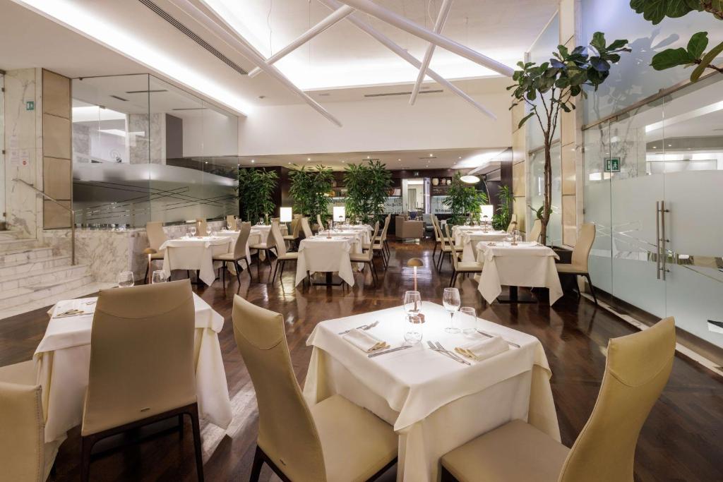 Restaurante do Best Western Plus Hotel Universo, em Roma, com mesas postas e decoração contemporânea.