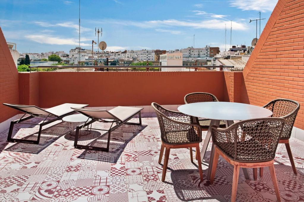 Varanda ensolarada com piso estampado e espreguiçadeiras no Eurostars Guadalquivir em Sevilha.