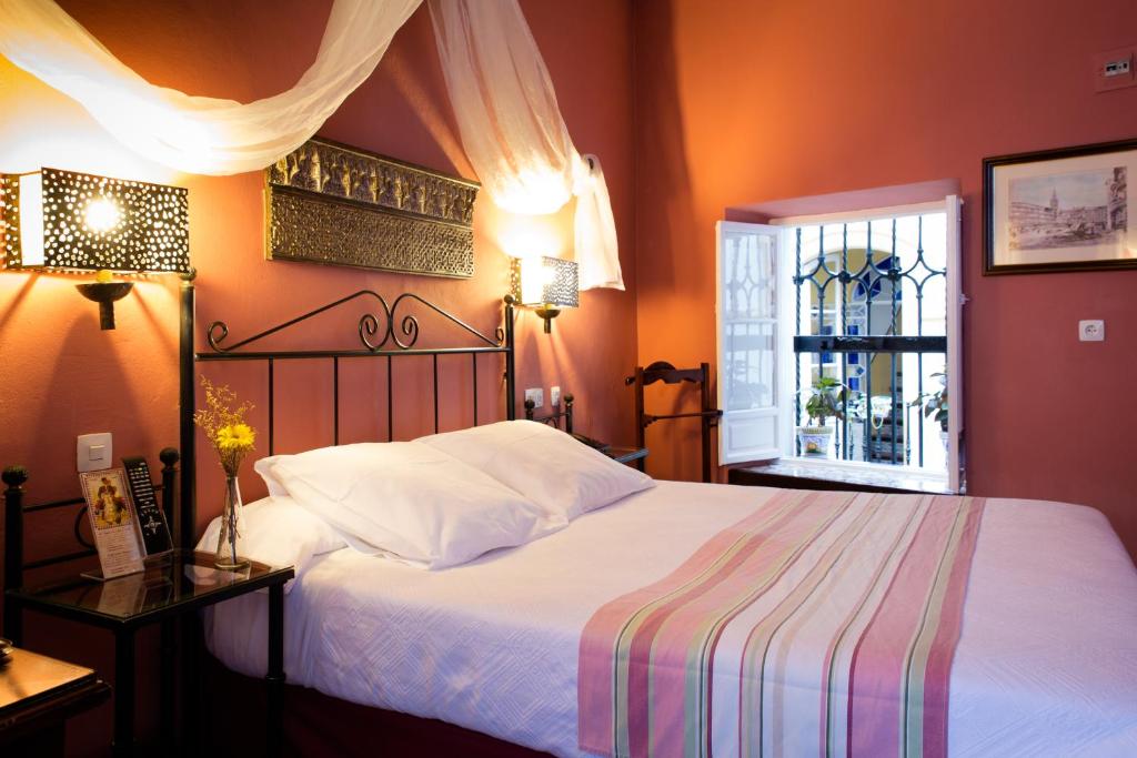 Quarto de hotel romântico com cama de ferro e dossel no Hotel Abanico Casa Palacio em Sevilha.