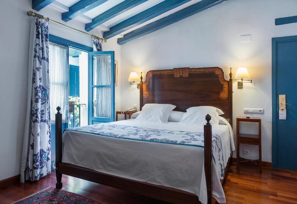 Quarto de hotel acolhedor com vigas de madeira e detalhes azuis no Hotel Las Casas de la Judería em Sevilha.