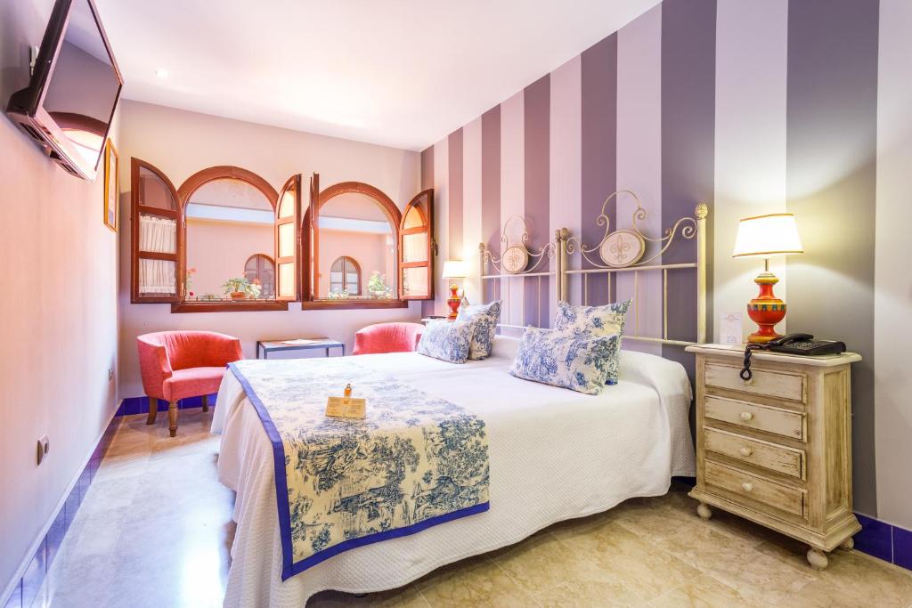 Quarto de hotel rústico com cabeceira de ferro e janelas de madeira no Patio de la Alameda em Sevilha.