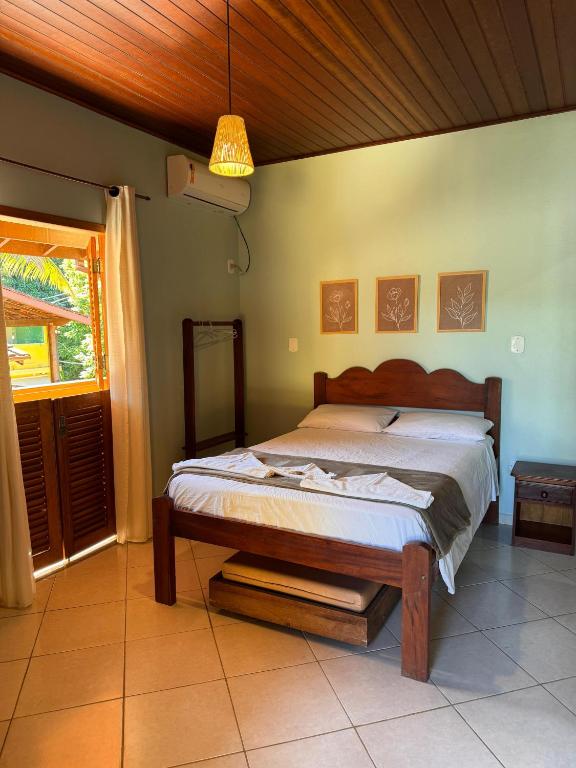 Quarto da Pousada Cabeça de Índio, em Trindade, com cama de madeira, varanda e teto revestido.