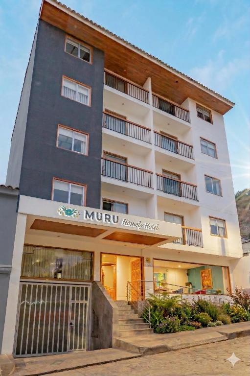 Fachada externa do MURU Homely Hotel com design moderno, varandas e letreiro iluminado.