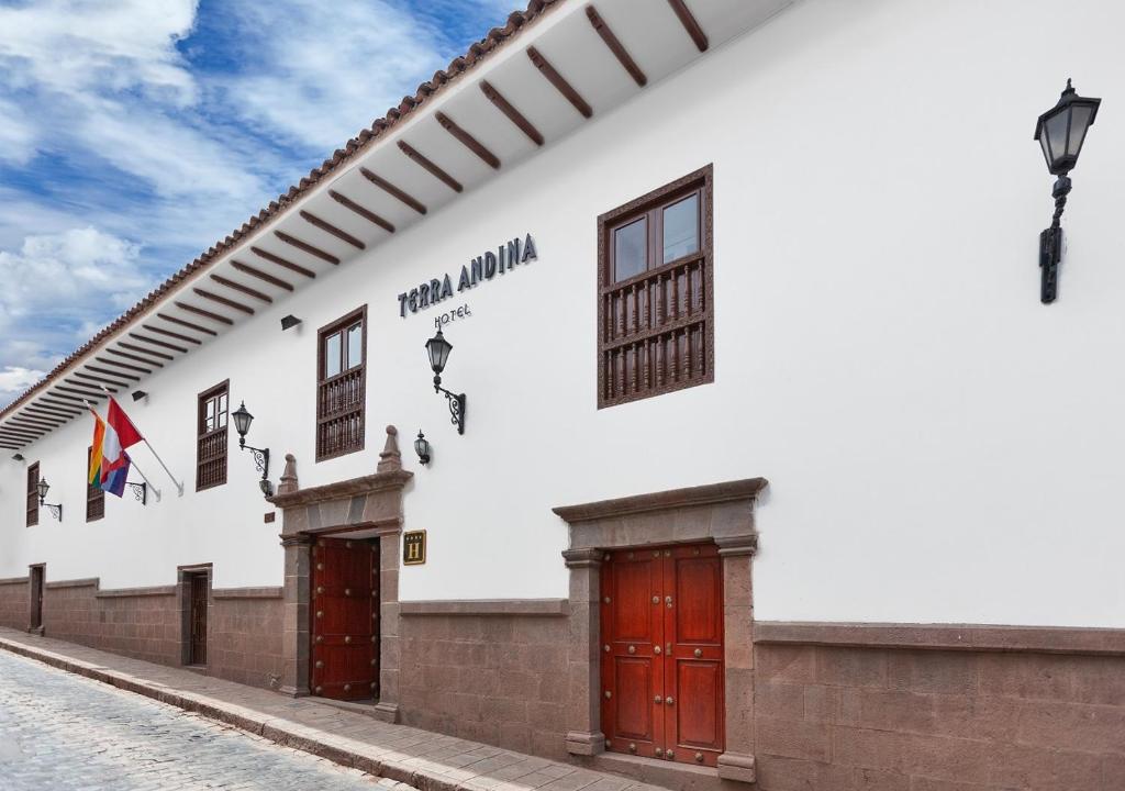 Fachada colonial do Terra Andina Colonial Mansion com paredes brancas, detalhes em pedra, portas de madeira e candeeiros de ferro forjado.