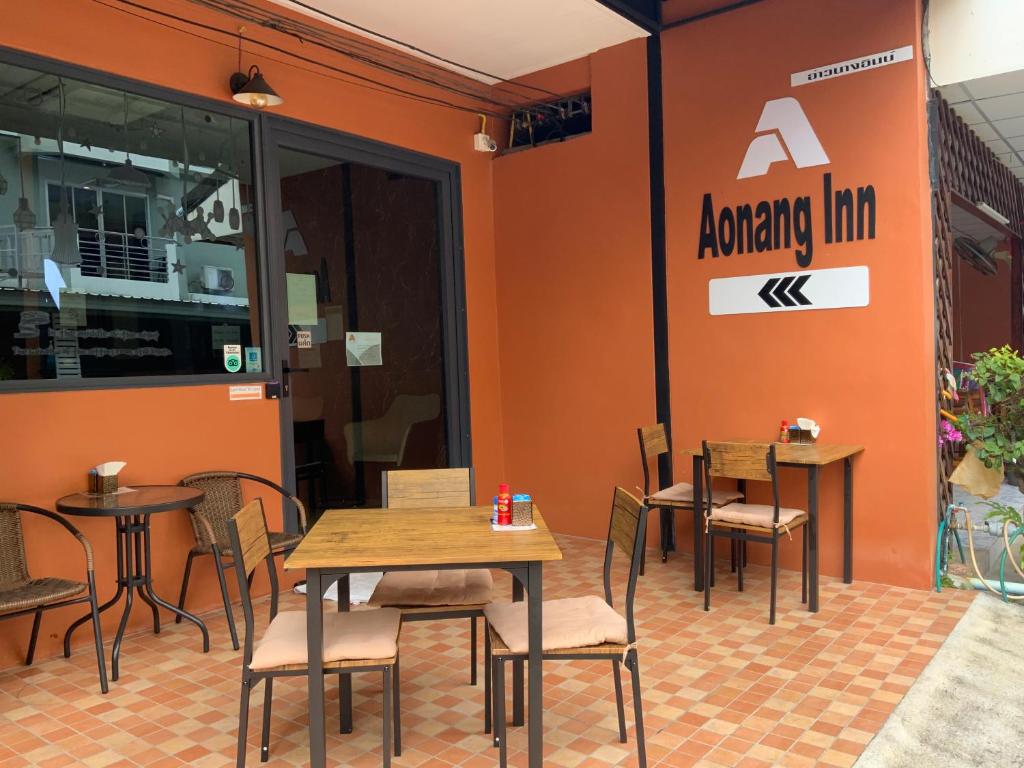 Área externa com mesas e fachada alaranjada no Aonang Inn.