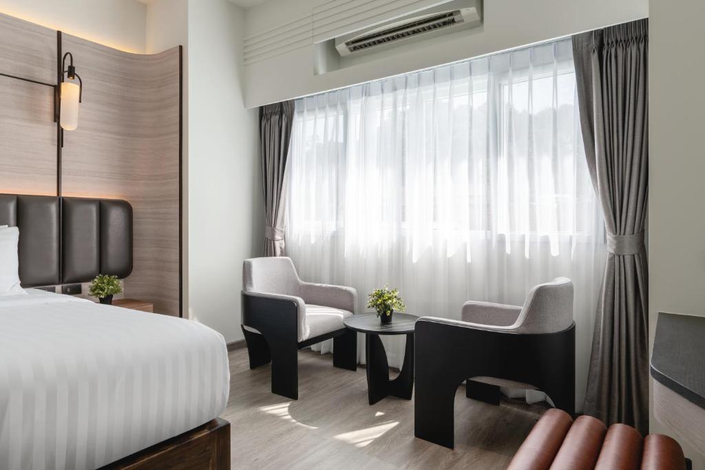 Quarto moderno no Panmanee Hotel com poltronas confortáveis perto da janela iluminada.